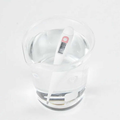 Thermometer in glass of water displaying waterprood digital bbt for tracking ovulation date